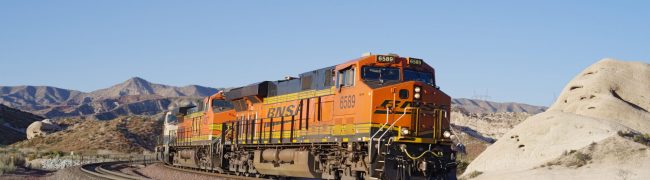 Cajon Pass, CA, USA - February 26, 2021: image showing a BNSF train traveling through the Mojave Desert. BNSF Railway is one of the largest freight railroad networks in North America.