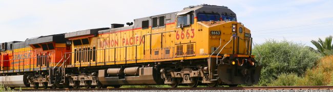 Mecca, California, United States - May 26, 2015: Freight train with both Union Pacific and BNSF engines on track next to California State Route 111.